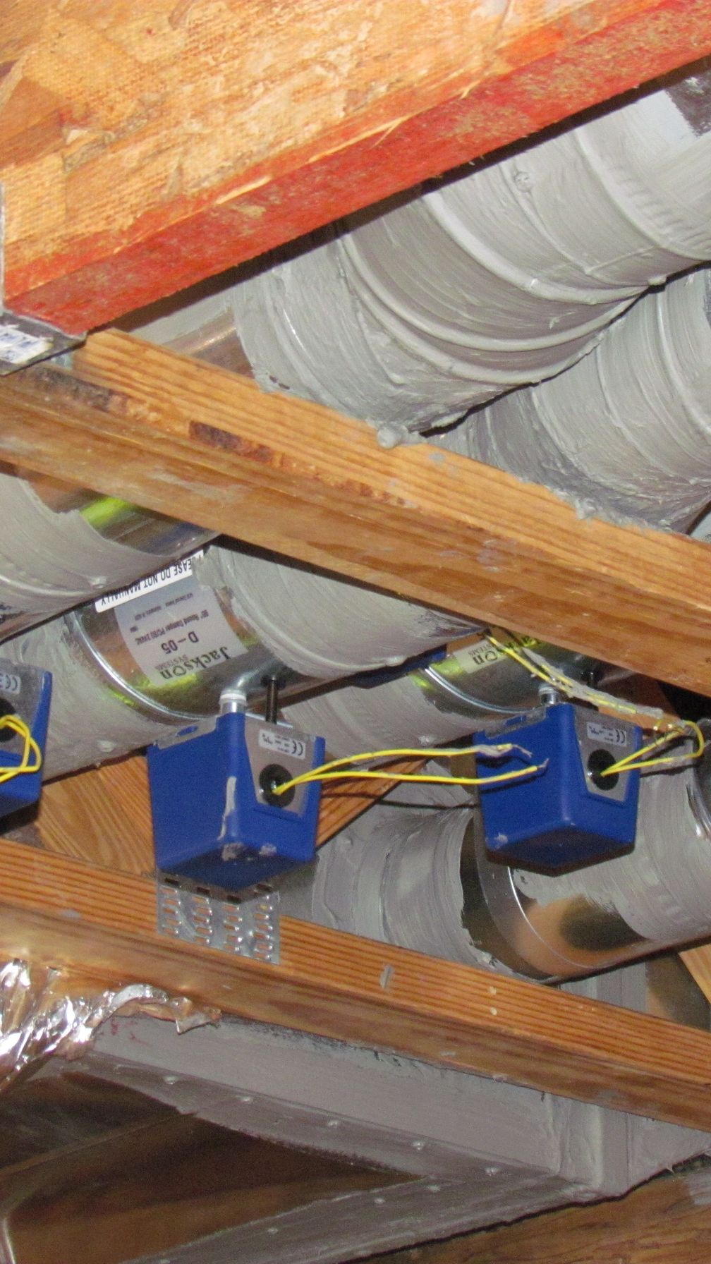 Insulated flexible air ducts run under the rafters of an attic